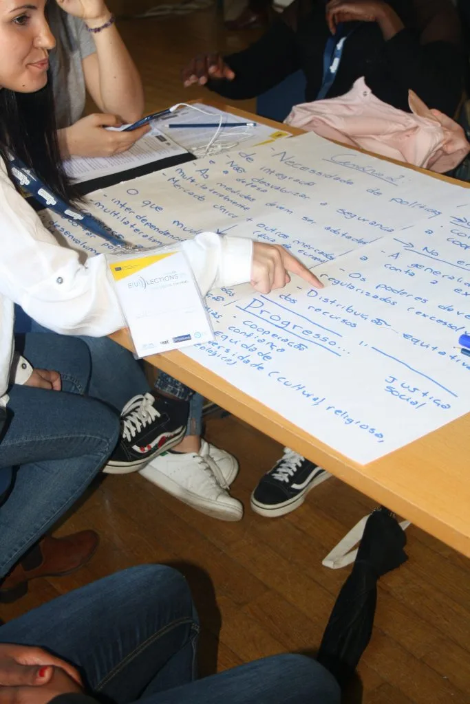 Handwritten poster spread over table with a participant pointing to it.