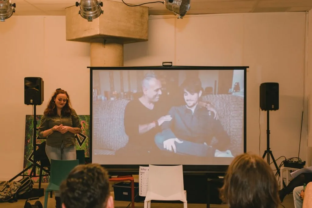 Woman presenting, image of two men.