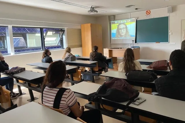 Another view of the back of the classroom, with the seated students paying attention to the representative speaking on the call.
