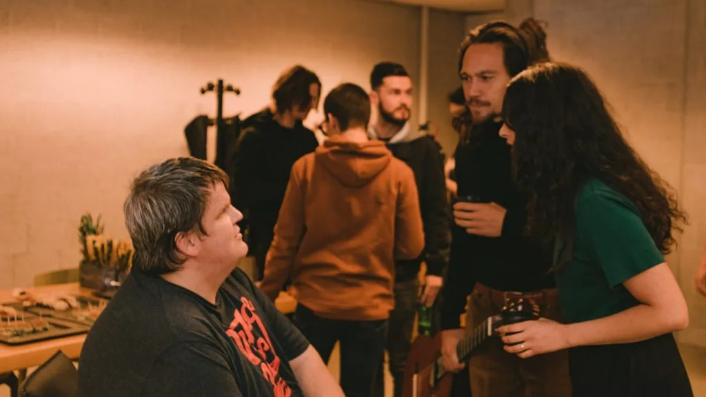 Participants and musicians chatting, seven people.