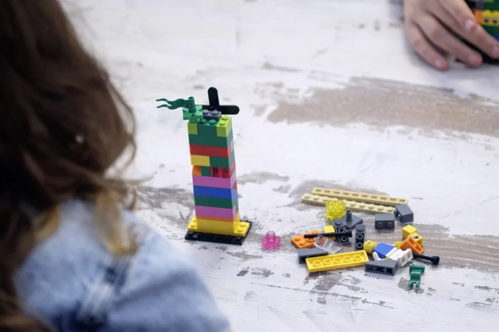 Lego construction with pieces spread over table and two participants.