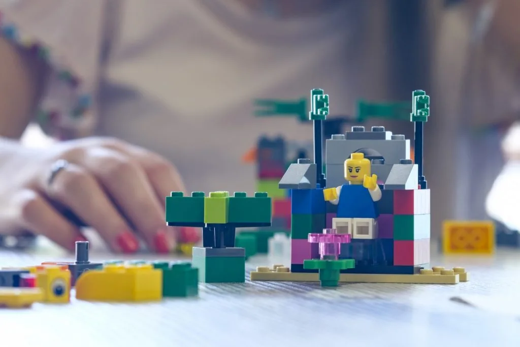 A Lego construction and its author's hand in the background.