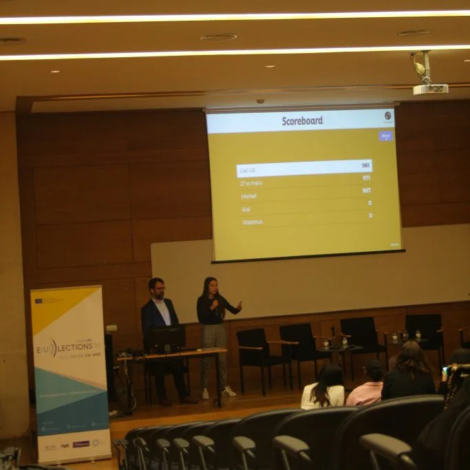 The quiz being presented by two Young Educators representatives to students in an auditorium.