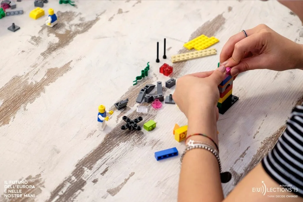 Participant making a Lego construction with pieces spread over the table.