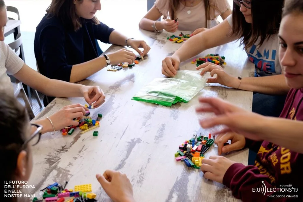 Six participants seated around a table using their Lego pieces.