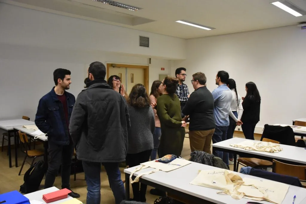 Participants forming two standing rows, facing one another, talking.
