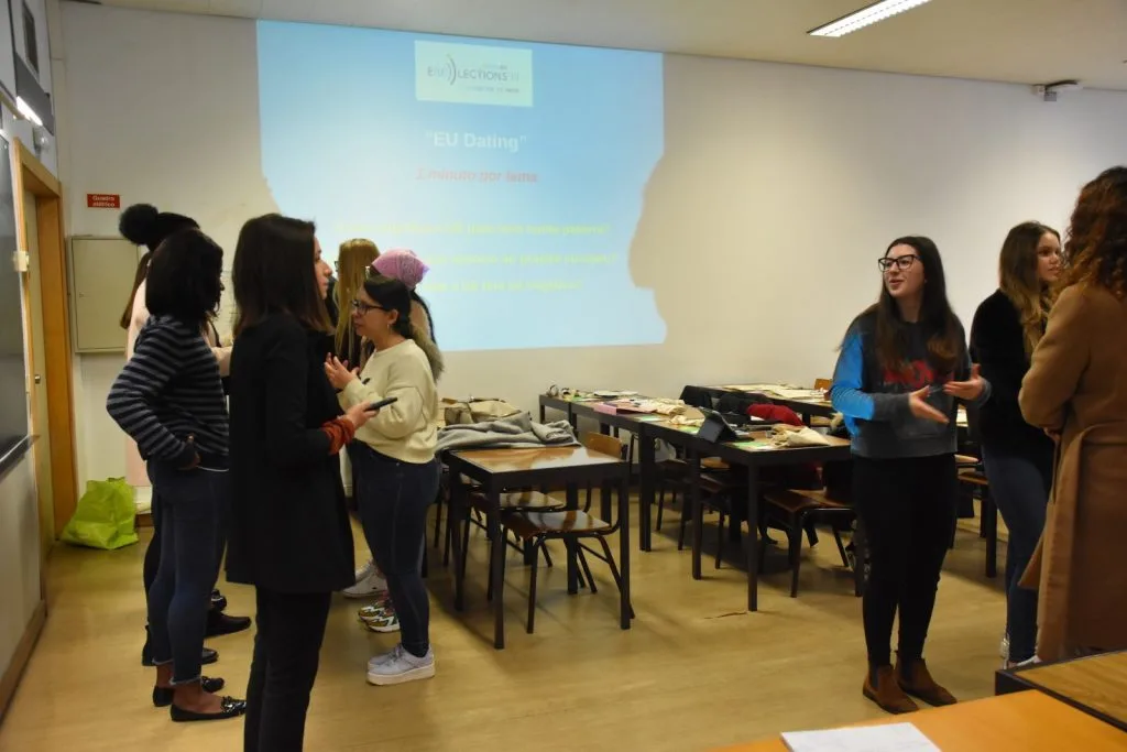 Participants forming two standing rows, facing one another, talking.