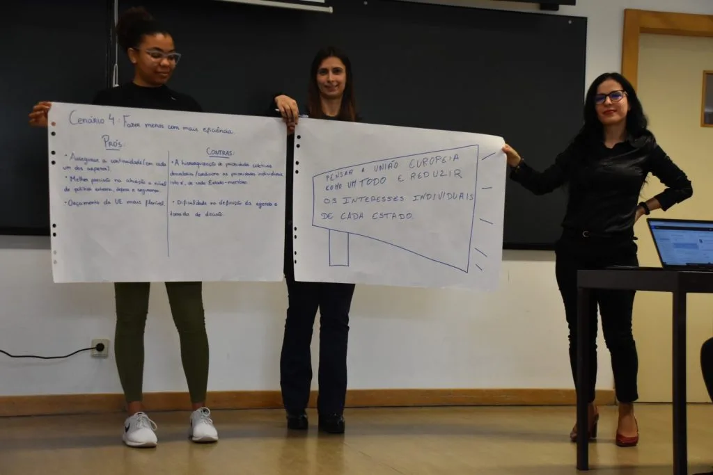Three students presenting their handwritten posters.