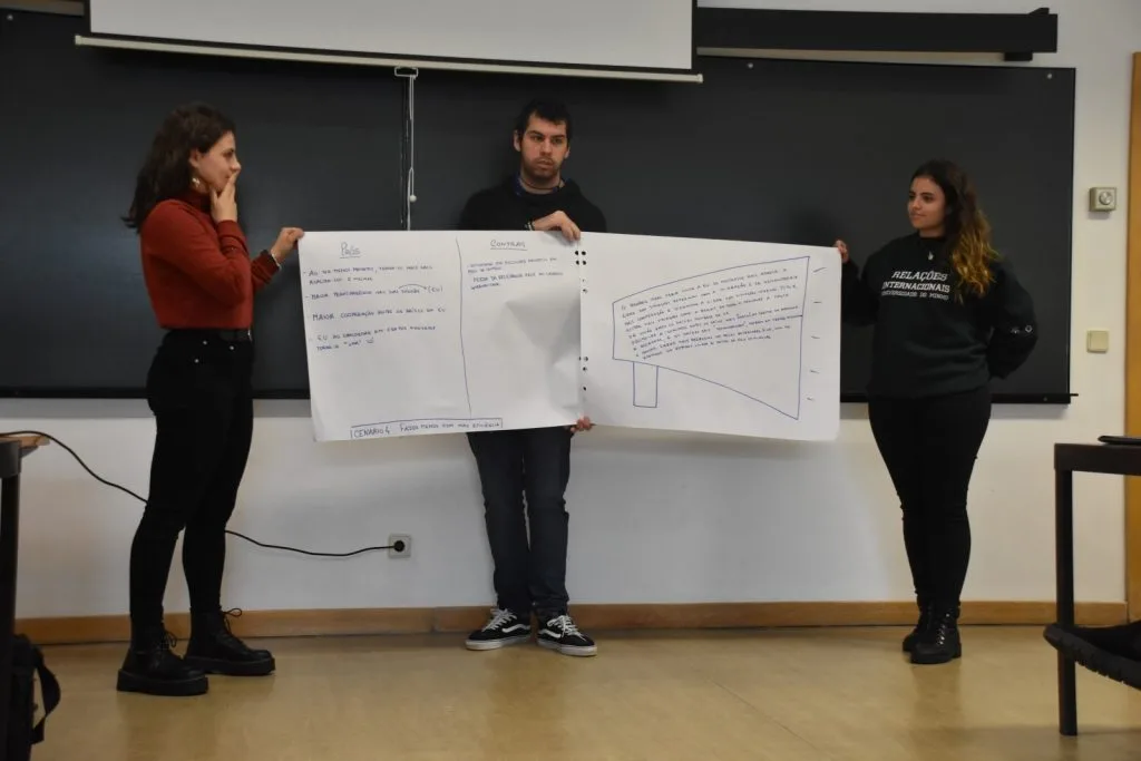 Three students presenting their handwritten posters.