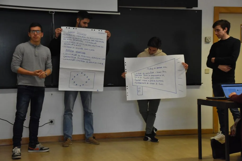 Four students presenting their handwritten posters.