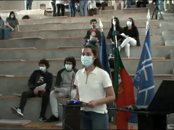 A student group representative standing in front of the other students, holding a paper while talking, sharing the conclusions of their group.