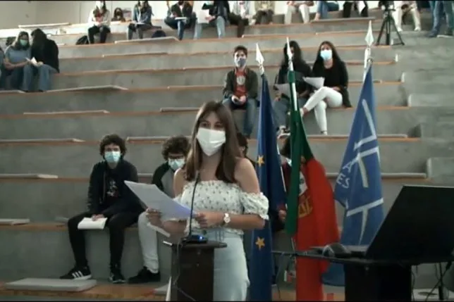 A student group representative standing in front of the other students, holding a paper while talking, sharing the conclusions of their group.