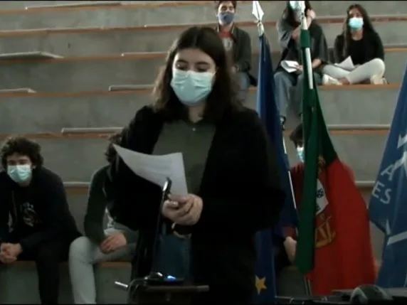 A student group representative standing in front of the other students, holding a paper while talking, sharing the conclusions of their group.