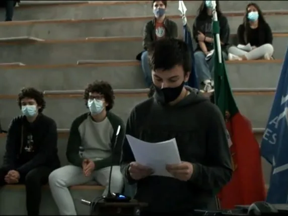 A student group representative standing in front of the other students, holding a paper while talking, sharing the conclusions of their group.