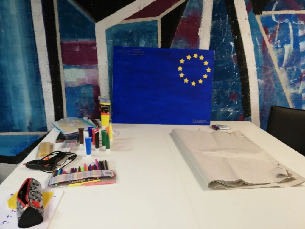Crafting table with materials and poster with only the blue background and European Union star circle done.
