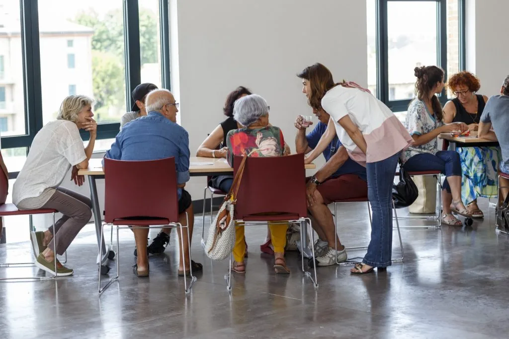 Participants seated around a table with woman hovering from the side.