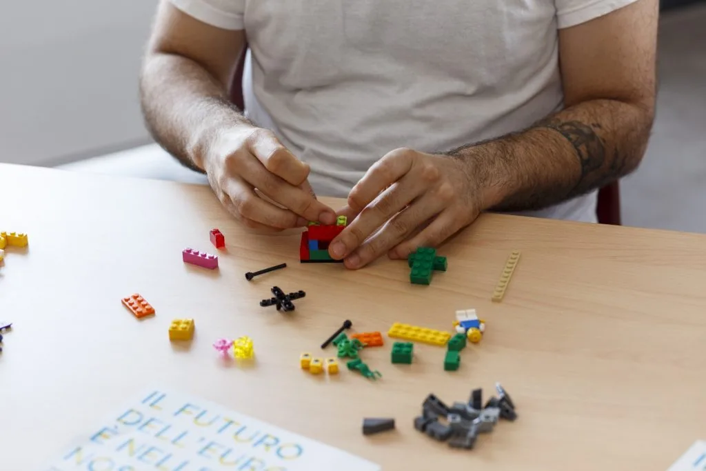 Participant's hands engaged in a construction and Lego pieces spread over the table.