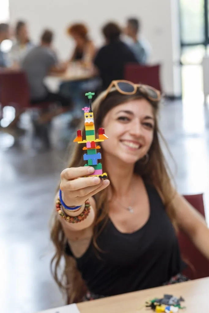 Participant smiling holding out their Lego construct.