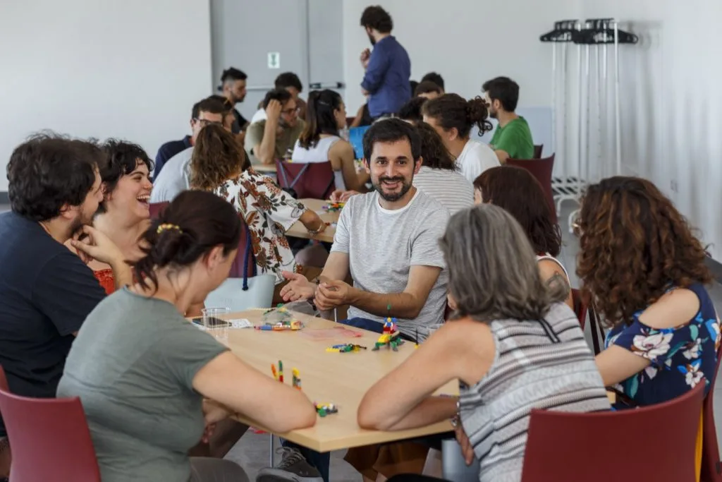 Participants seated around multiple tables with Lego pieces in front of them.