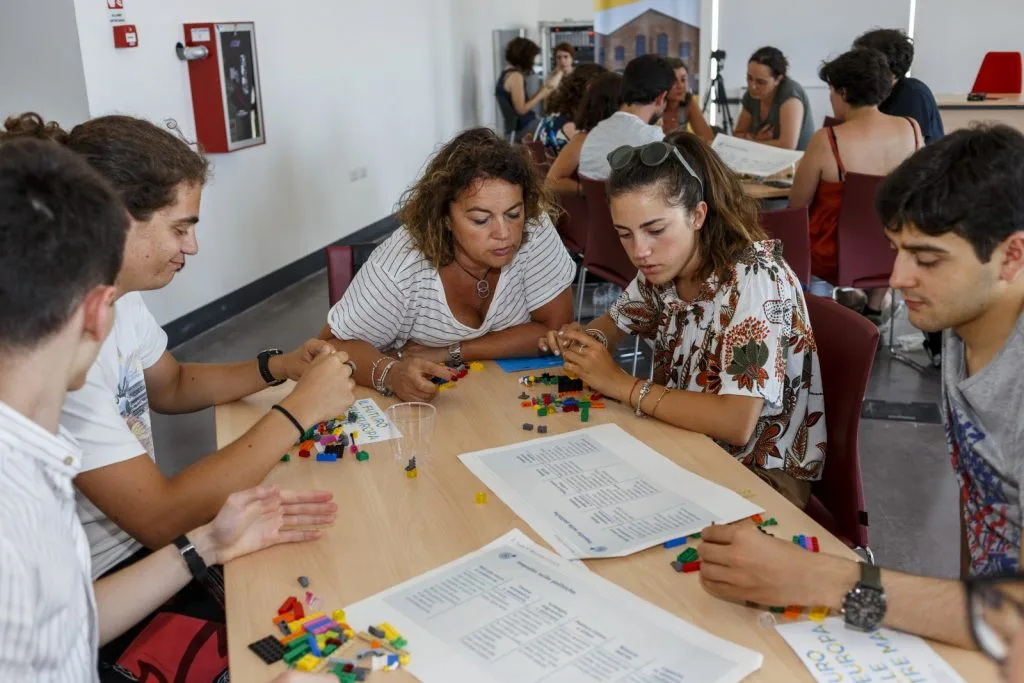 Five participants talking over table with Lego pieces and paper sheets describing the five scenarios for the future of Europe.