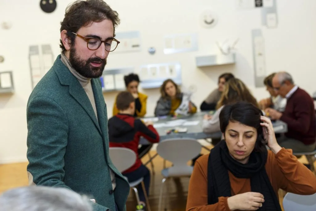 Tables with participants seated and a representative speaking, standing beside a participant.