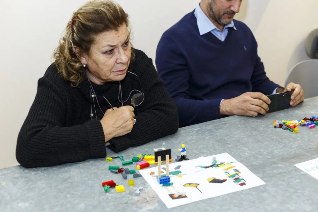 Two seated participants with Lego pieces spread in front of them.