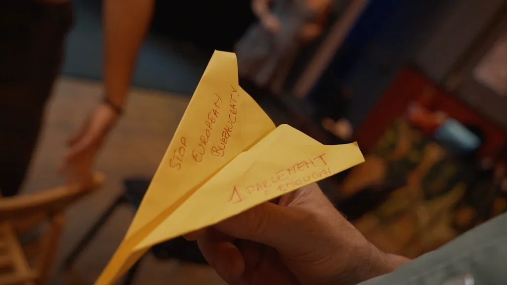 Participant holding paper airplane with handwritten words.